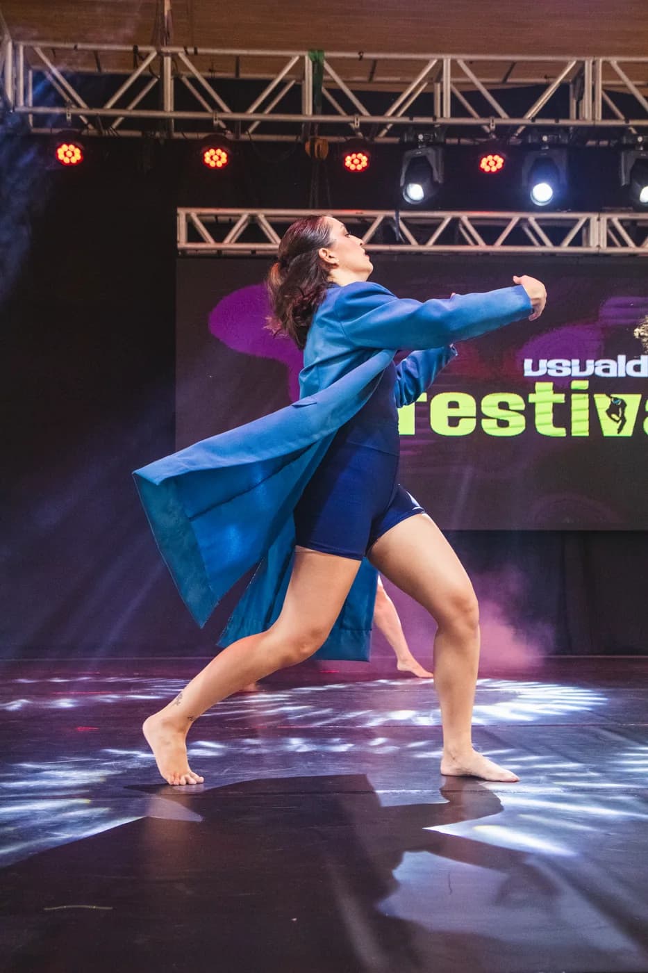 Bailarina solo de dança contemporânea com sobretudo azul no palco da Usualdance Festival 2026